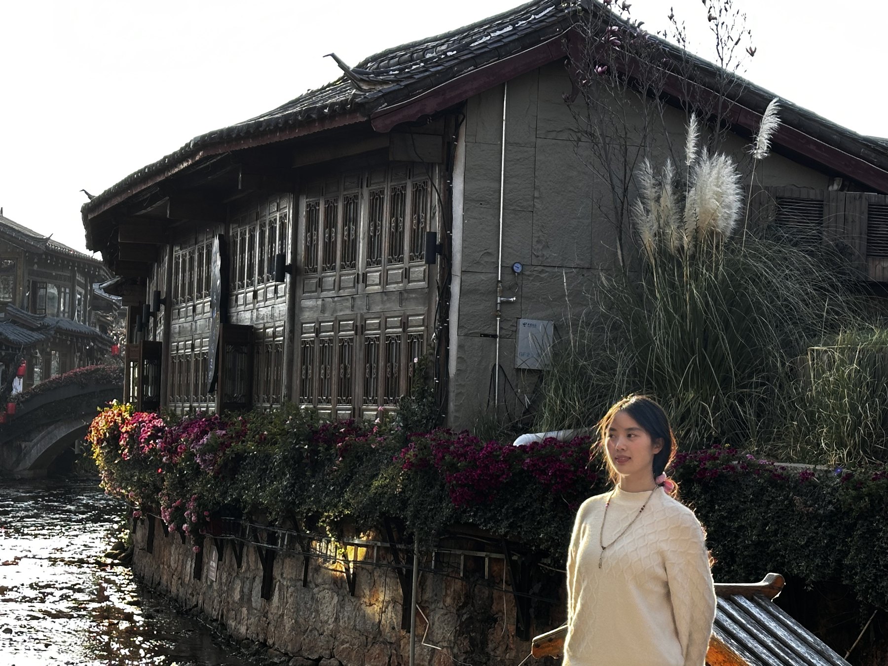 许琬苓站在丽江水边古建筑前