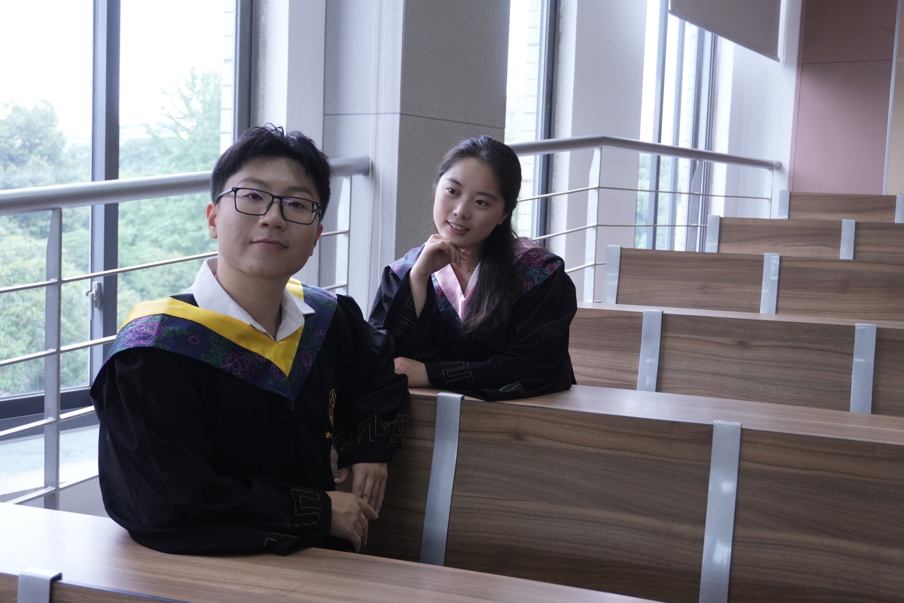 张桐宇和许琬苓穿学士服在教室摆姿势合照