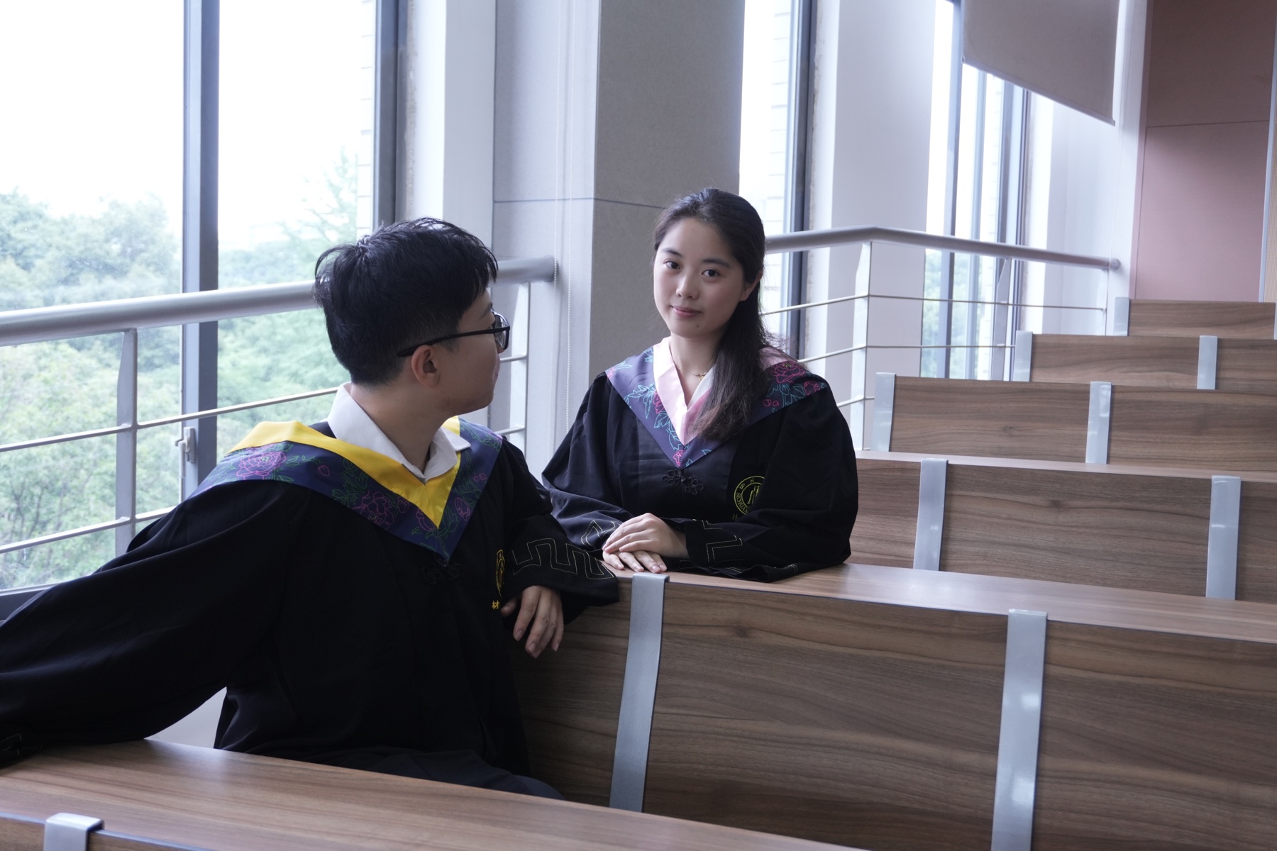 张桐宇和许琬苓穿学士服坐在阶梯教室