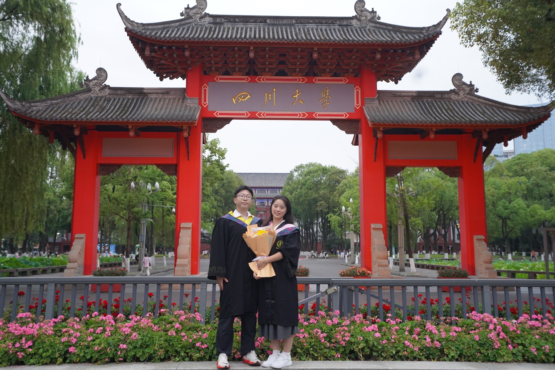 张桐宇和许琬苓穿学士服在四川大学校门前合照