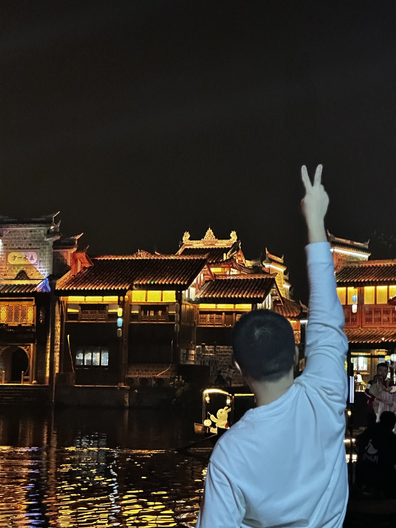 张桐宇在宜宾李庄夜景前举手比耶
